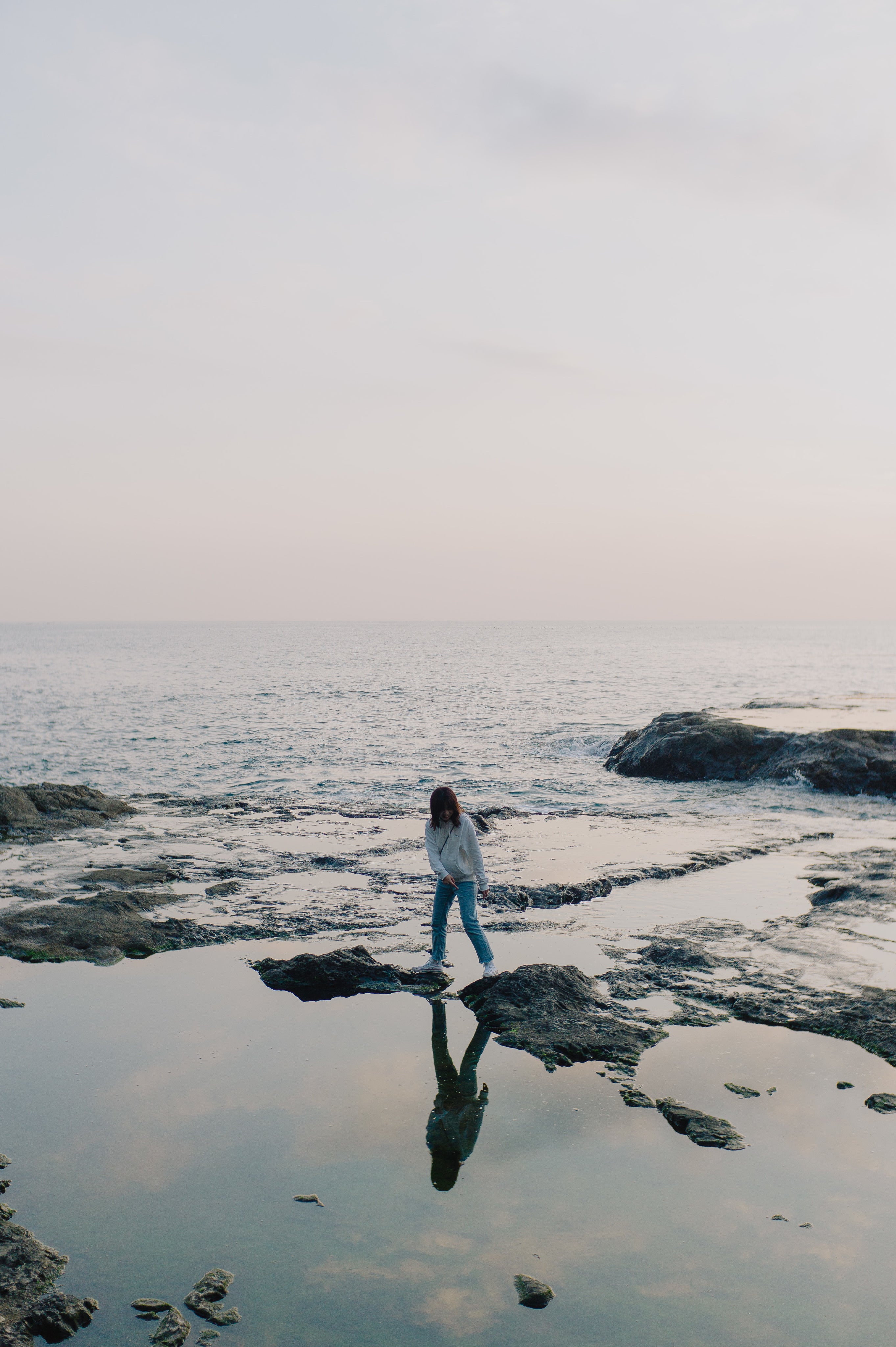 person stand on rock poking out of ocean